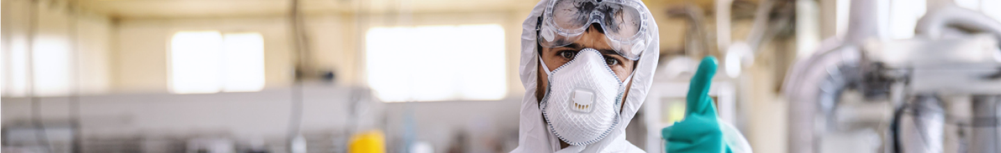 Trabajador con mascarilla y traje de protección antivacterias mirando a la camara y dando un dedo arriba de aprovación